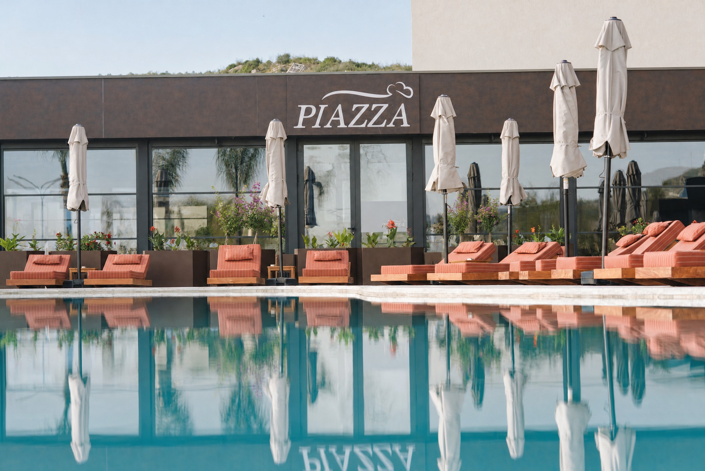 Piazza — fasada e pasqyruar në sipërfaqen e qetë të pishinës