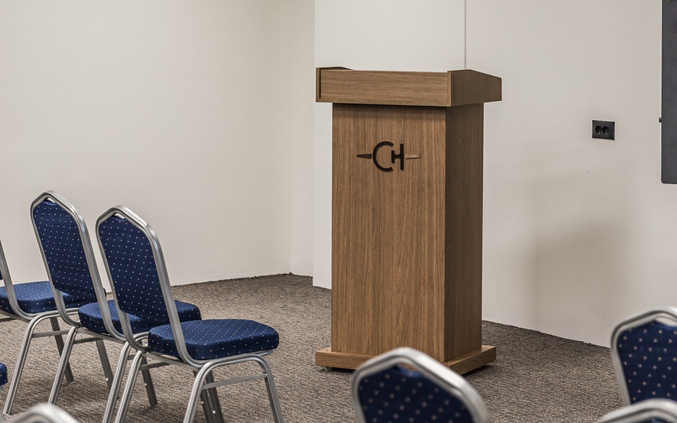 Chaonian's conference hall — the oak lectern with the CH monogram, banquet chairs beside it