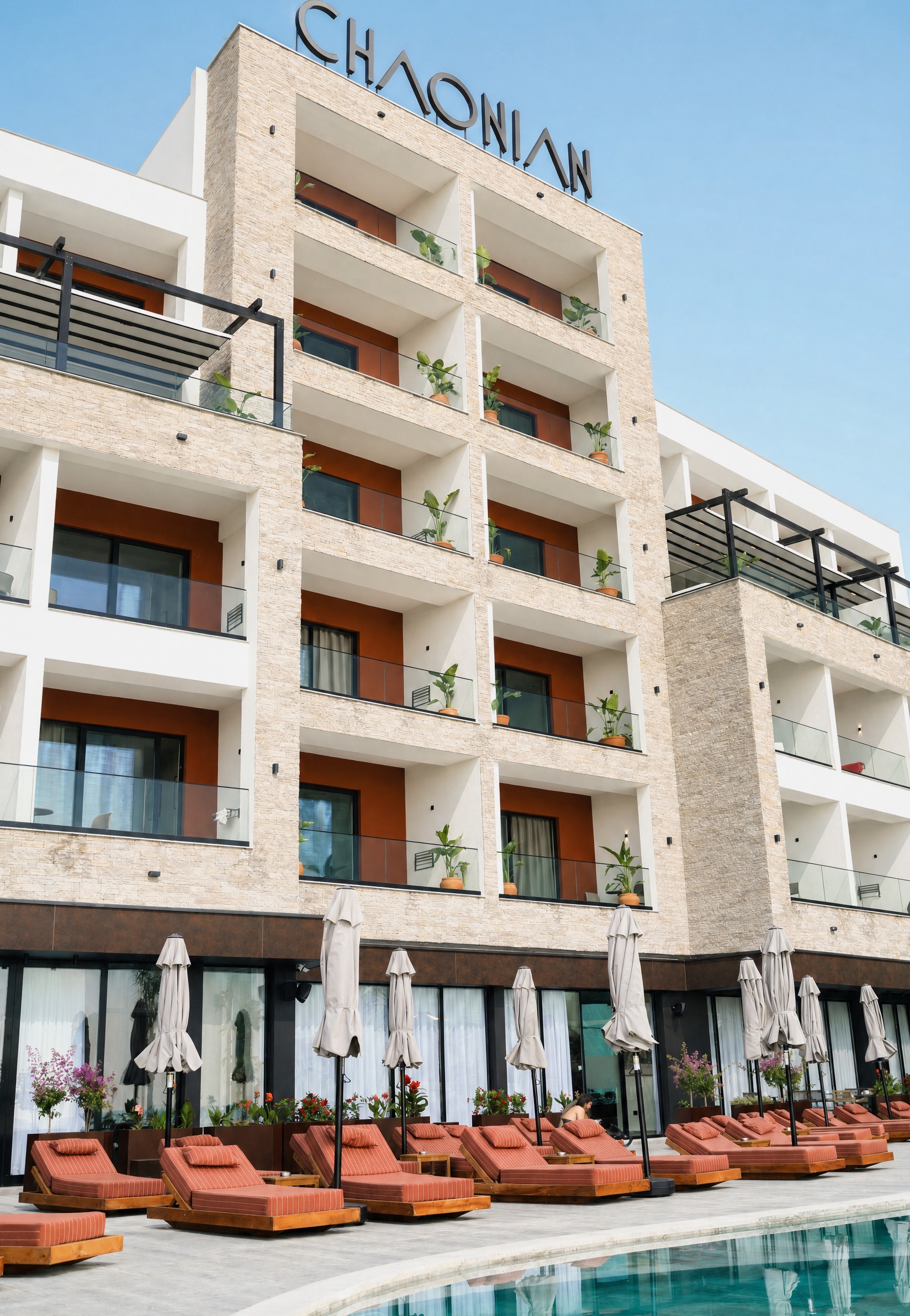 Chaonian Hotel — tarraca e pishinës dhe rreshtat e shezlongëve terrakota